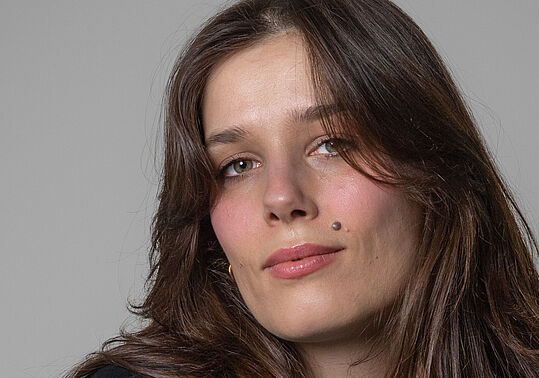 Tara-Louise_Wittwer_WUK_2025_(c)_LewisJones Ein Bild einer weiblich gelesenen Person mit langen dunklen Haaren