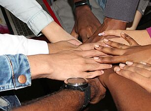 Foto von Rineshkumar Ghirao auf Unsplash Mehrere Hände liegen übereinander in der Mitte eines Kreises