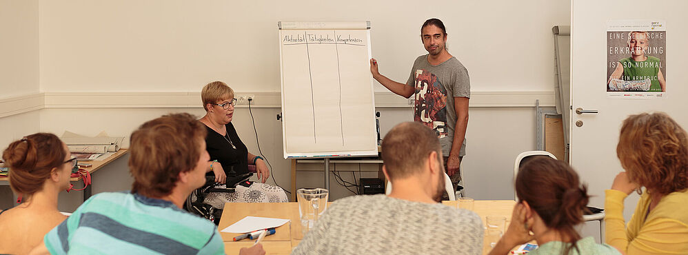 Person präsentiert an Flipchart in Workshop zur Bildungsberatung vor Gruppe von Teilnehmenden