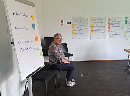 Eine Selbstverteterin sitzt vor einem Flipchart