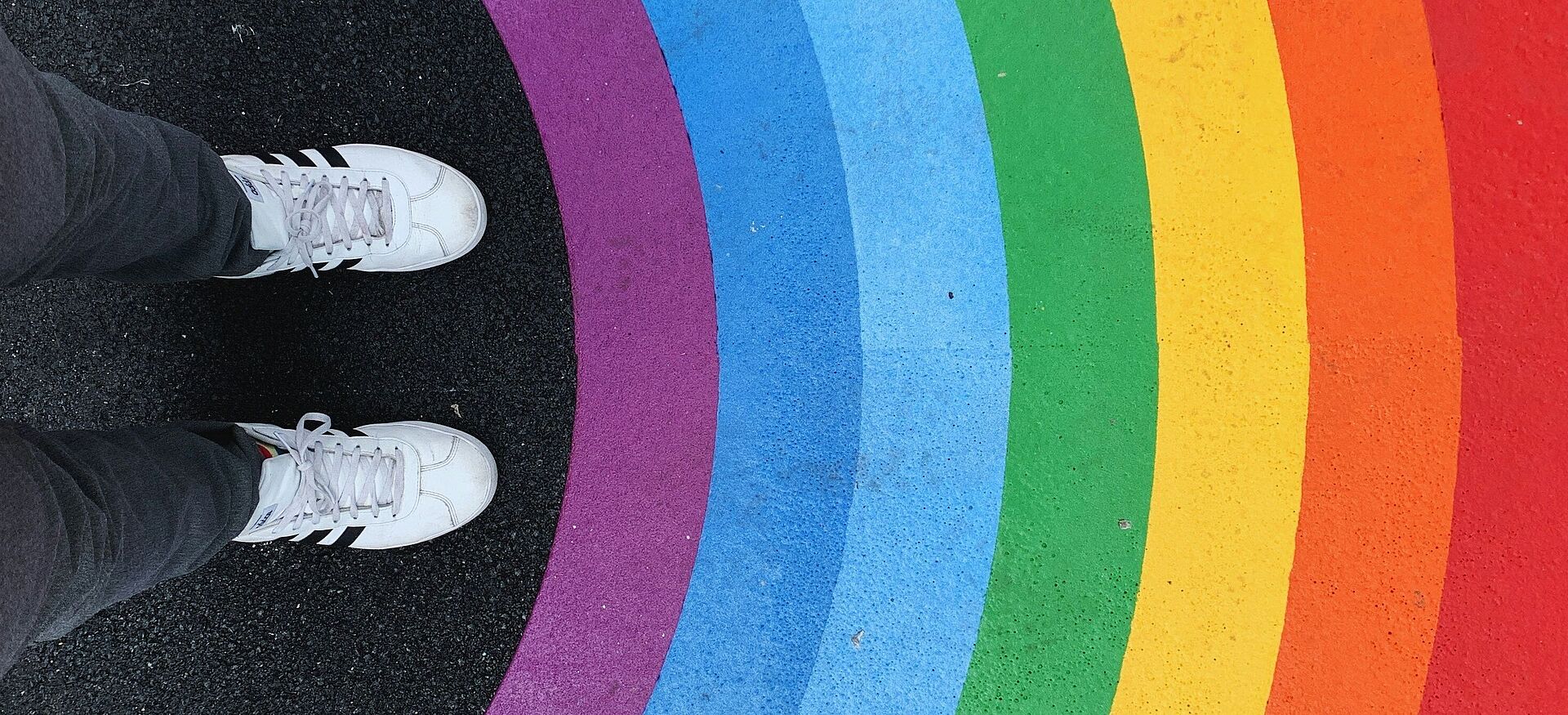 Füße einer Person vor einem auf den Boden gemalten Regenbogen