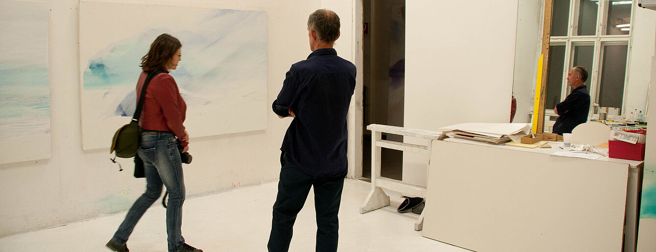 Zwei Personen betrachten ein abstraktes Gemälde in einem hellen Raum während einer Hausführung